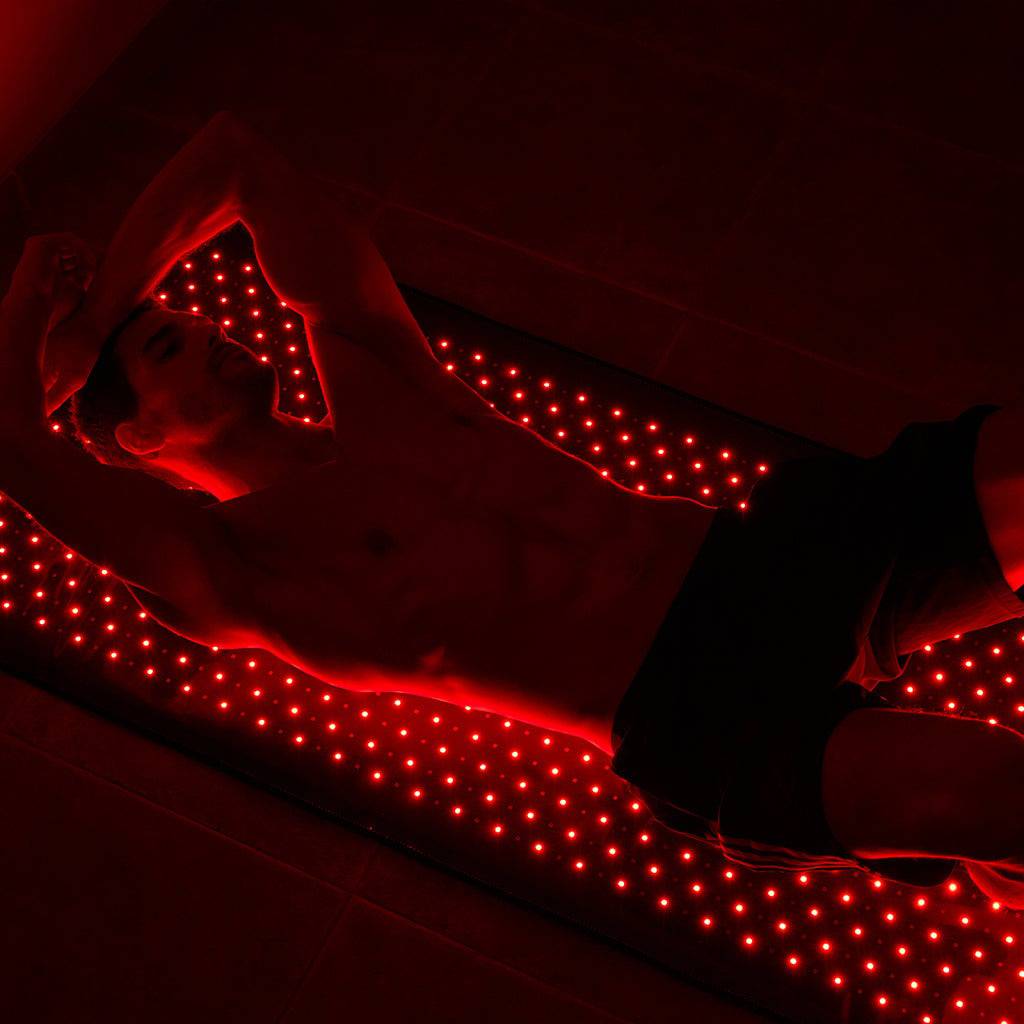 Man using Haloral Full Body Red Light Therapy Mat for muscle recovery and relaxation.
