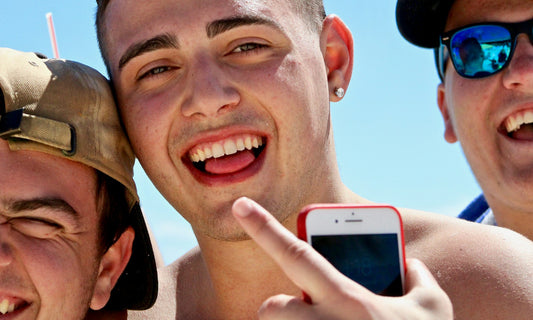 Young man with a radiant, confident smile enjoying a sunny day outdoors, showcasing bright white teeth.