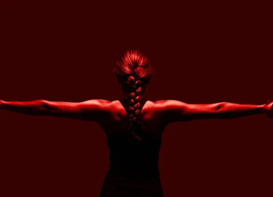 Woman using red light therapy for muscle recovery, showcasing strength and athletic performance.