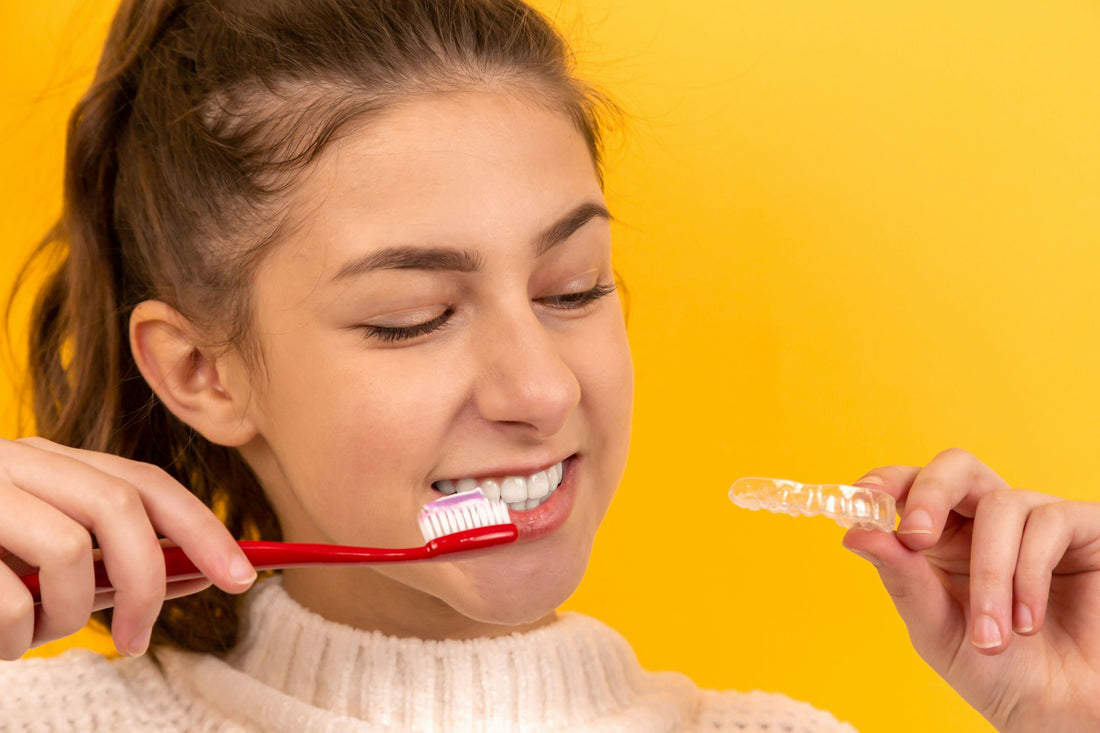 A young woman applying whitening gel to her aligner while holding a toothbrush, representing safe home whitening care.