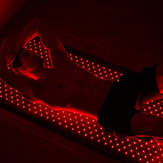 Man using Haloral Full Body Red Light Therapy Mat for muscle recovery and relaxation.