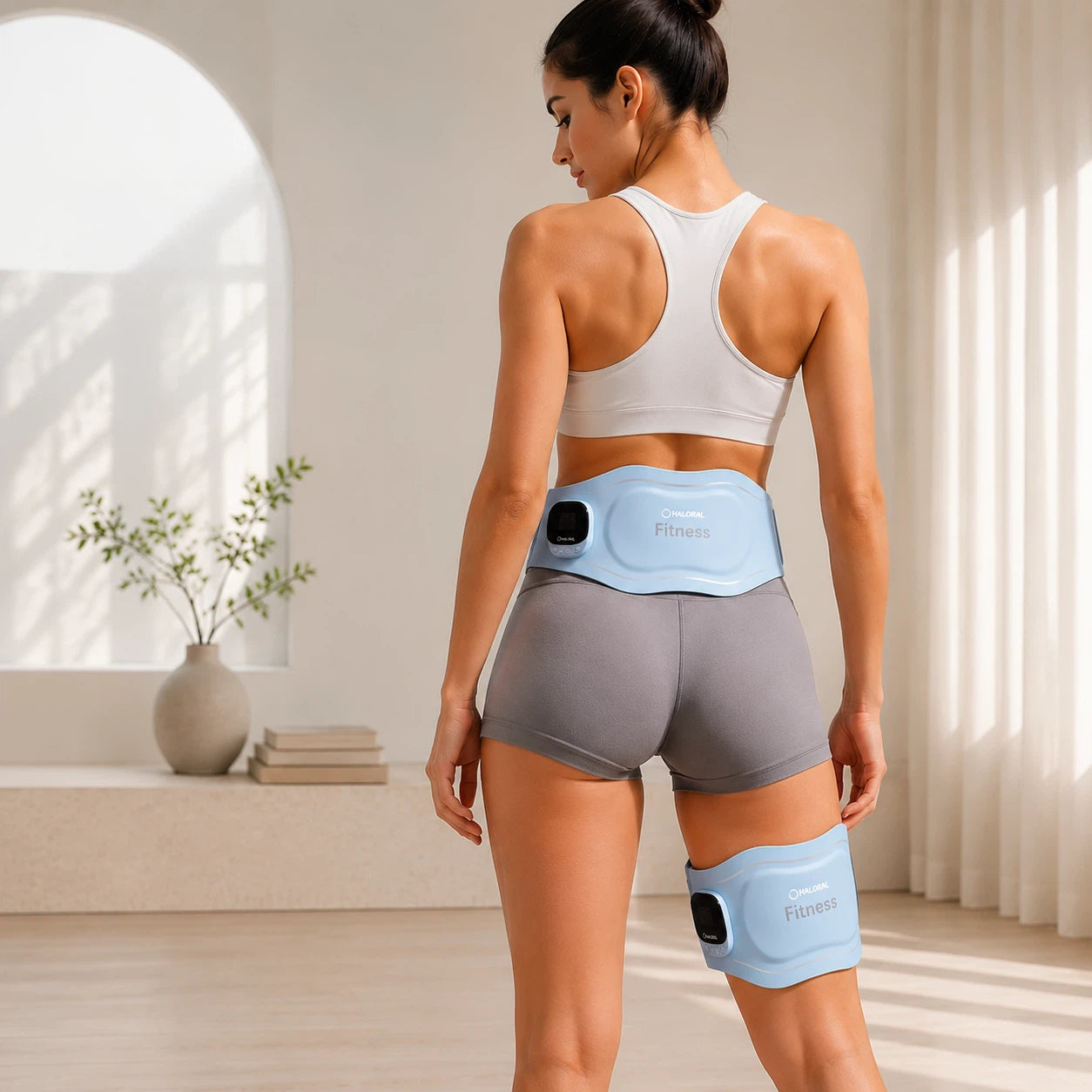 Woman wearing Haloral EMS toning belts on the lower back and thigh for targeted muscle stimulation and recovery support
